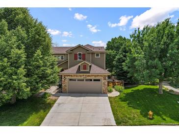 Charming two-story home featuring a stone-accented garage and a well-manicured front lawn with mature trees at 8532 W Eden Dr, Littleton, CO 80127