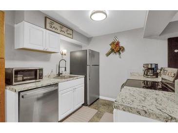 Compact kitchen features stainless steel appliances, light countertops, and white cabinets at 1611 Garfield Ave # 2, Louisville, CO 80027