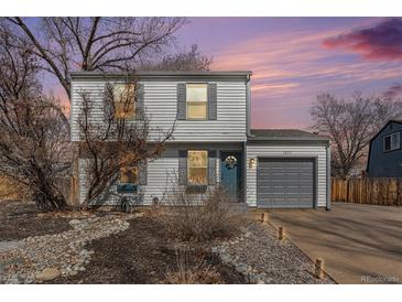 Charming two-story home with gray siding, a one-car garage, and xeriscaped front yard at dusk at 1277 W 135Th Pl, Broomfield, CO 80234