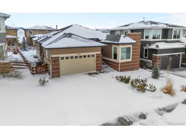 Brick ranch home with attached garage and snow-covered yard at 9557 Juniper Way, Arvada, CO 80007