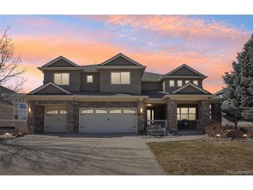 Charming two-story home with a three-car garage and well-maintained front yard under a beautiful pink and orange sky at 8131 S Coolidge Way, Aurora, CO 80016