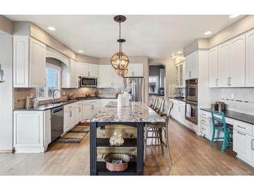 Spacious kitchen with white cabinets, stainless appliances, granite counters and large island at 8131 S Coolidge Way, Aurora, CO 80016