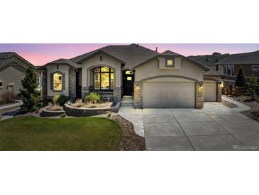 Charming stucco home featuring a well-manicured lawn, stone accents, and an attached two-car garage at 3255 Waterfront Dr, Monument, CO 80132