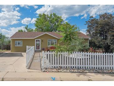 Charming single-story home featuring a welcoming entrance, white picket fence, and well-maintained landscaping at 1817 S Perry Way, Denver, CO 80219