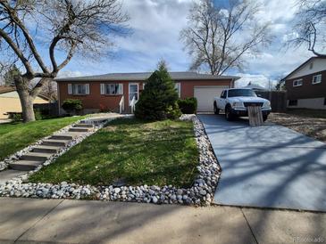 Charming brick home with a well-manicured lawn, rock border, and concrete driveway at 12116 W Texas Dr, Lakewood, CO 80228
