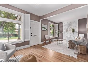 Bright living room featuring hardwood floors, large windows, and a decorative fireplace at 368 S Humboldt St, Denver, CO 80209
