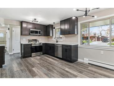 A well-lit kitchen features stainless steel appliances, granite countertops and hardwood floors at 6913 Teller Ct, Arvada, CO 80003