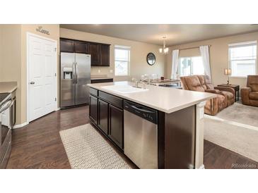 Stylish kitchen boasts dark cabinets, stainless steel appliances, and a large island with seating at 19468 E 65Th Pl, Aurora, CO 80019