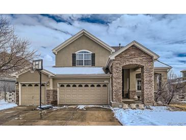 Charming two-story home showcasing a 3-car garage, stone accents, and a welcoming covered entryway at 14096 Roaring Fork Cir, Broomfield, CO 80023