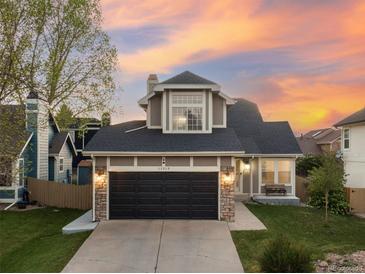 Charming two-story home with a well-maintained lawn and a two-car garage with stone accents, under a vibrant sunset sky at 11519 Wray Ct, Parker, CO 80134