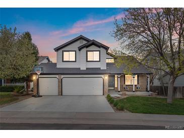 Charming two-story home with a three-car garage and a well-manicured lawn under a colorful sunset at 20650 Parker Vista Cir, Parker, CO 80138