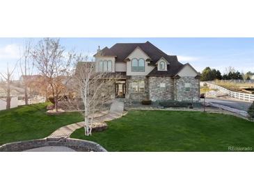 Two-story house with stone facade, landscaped lawn, and walkway at 9965 E 143Rd Way, Brighton, CO 80602