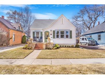 Charming white cottage with a well-manicured lawn and inviting front porch at 821 Collyer St, Longmont, CO 80501