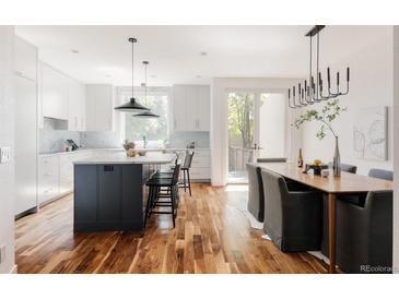 Bright, modern kitchen featuring white cabinets, wood floors, and center island with marble countertops at 3130 Wyandot St, Denver, CO 80211