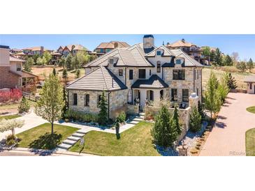 Stunning stone-clad home featuring a multi-gable roof, manicured lawn, and a welcoming stone walkway at 10704 Flowerburst Ct, Highlands Ranch, CO 80126
