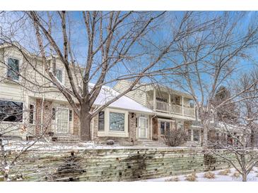 Charming townhomes showcase brick accents, bay windows, and covered balconies amidst snow-dusted landscaping at 7729 S Cove Cir, Centennial, CO 80122