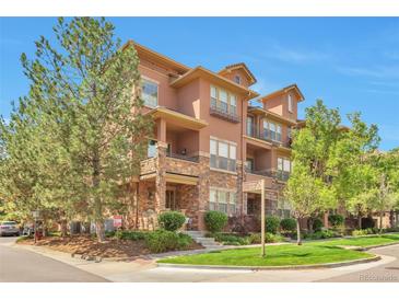 Charming multi-story condo with stone accents, lush landscaping, and signage at the corner of Oak Street at 10152 Inverness Main St, Englewood, CO 80112