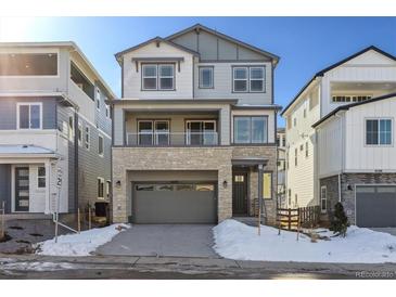 Two-story home with gray siding, stone accents, and a two-car garage at 8570 Eagle River St, Littleton, CO 80125