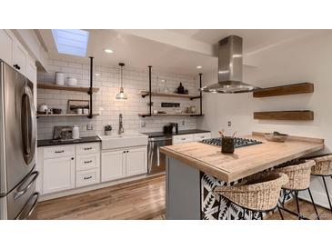 Bright kitchen featuring a butcher block island, stainless steel appliances and decorative open shelving at 1571 Glencoe St, Denver, CO 80220