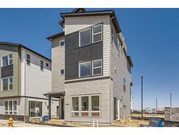 Modern three-story home with brick accents, large windows, and contemporary design at 10880 E Hinsdale Cir, Centennial, CO 80112