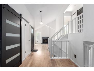 Bright foyer with hardwood floors, black sliding doors, white stairway and fireplace in the background at 772 Ivywood Ct, Highlands Ranch, CO 80126