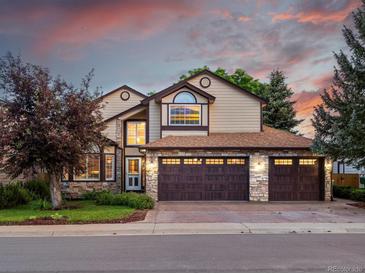 Charming two-story home with a three-car garage and stone accents, set against a beautiful sunset sky at 10954 W 100Th Way, Broomfield, CO 80021