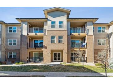 Three-story apartment building with brick and neutral siding, balconies, and ample parking at 15345 W 64Th Ln # 304, Arvada, CO 80007