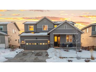 Two-story house with gray siding, large windows, and a three-car garage at 9295 Dunraven Loop, Arvada, CO 80007