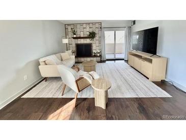 Inviting living room featuring a fireplace, stylish seating, and access to a balcony at 7255 E Quincy Ave # 309, Denver, CO 80237