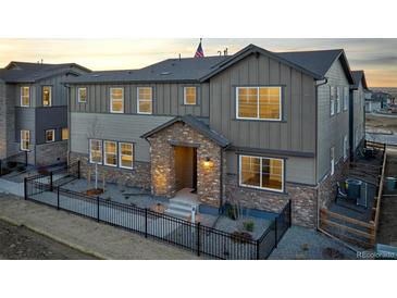 Beautiful two-story home featuring a stone entryway, black metal fence, and neutral-colored siding at sunset at 23731 E 40Th Ave, Aurora, CO 80019