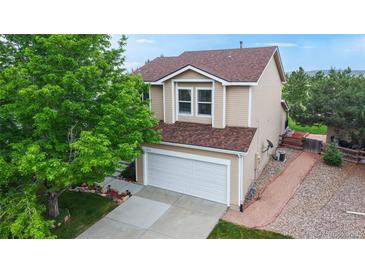 Two-story home with tan siding, new brown shingle roof and well-maintained landscaping at 7270 Marmot Ridge Pl, Littleton, CO 80125
