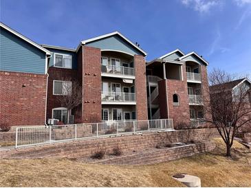 Brick condominium building featuring blue siding and white balconies on each level at 2675 S Danube Way # 302, Aurora, CO 80013