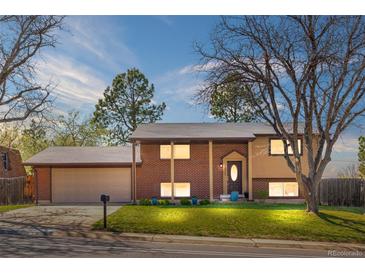Charming brick home featuring a well-maintained lawn, mature trees, and an attached two-car garage at 10429 Quivas St, Northglenn, CO 80234