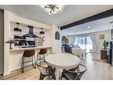 Bright open-concept living and dining area with modern kitchen and light-filled living room with sliding door at 12131 Melody Dr # 201, Denver, CO 80234