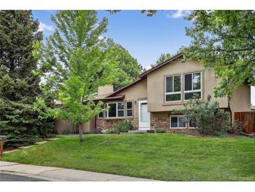 Inviting exterior showcasing a well-maintained lawn and charming stone accents, with abundant mature trees for shade at 18445 W 59Th Dr, Golden, CO 80403