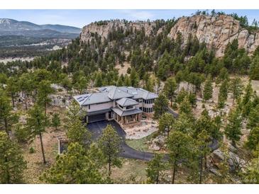 Stunning luxury home with mountain views surrounded by lush trees and unique rock formations at 6767 Timbers Dr, Evergreen, CO 80439