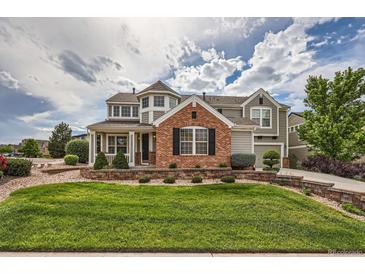 Beautiful two story home with brick and siding and manicured front lawn and garden at 8469 Winter Berry Dr, Castle Pines, CO 80108