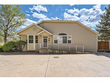 Tan home with a ramp leading to the front door and large concrete driveway at 8843 W Phillips Dr, Littleton, CO 80128