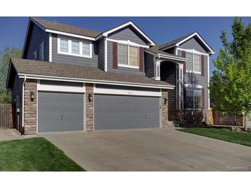 Two-story home with a three car garage, stone accents, and mature lawn at 331 Las Lomas St, Brighton, CO 80601