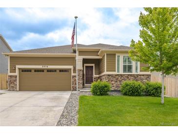 Ranch home with a two-car garage, stone accents, neutral paint, well-kept lawn and an American flag at 3936 Costillo Ct, Brighton, CO 80601