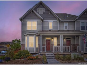 Charming two-story home featuring a cozy front porch, landscaped yard, and a beautiful dusk sky at 3921 E 141St Ave, Thornton, CO 80602
