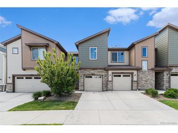 Modern townhome with stone accents, attached garage, and well-maintained landscaping under a blue sky at 9757 Ash Ln, Thornton, CO 80229
