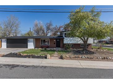 Charming home features brick accents, mature trees, an attached garage, and well-maintained landscaping at 6013 W 62Nd Ave, Arvada, CO 80033