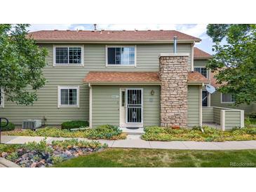 Inviting two-story townhome featuring a stone chimney and well-maintained landscaping at 8406 Everett Way # C, Arvada, CO 80005