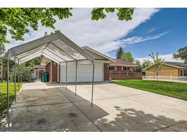 Brick home with an attached garage, concrete driveway with a car port, and well maintained lawn at 13472 E Dakota Ave, Aurora, CO 80012