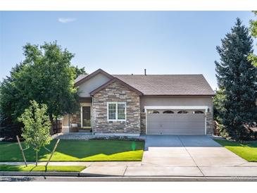 Charming single-story home features a stone facade, well-manicured lawn, and an attached two-car garage at 10482 Billings St, Commerce City, CO 80022