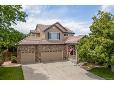 Charming two-story home featuring a brick facade, three-car garage, tile roof, and an inviting front porch with American flag at 13753 Monroe St, Thornton, CO 80602