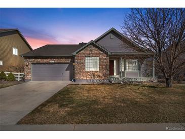 Charming home featuring a stone facade, two-car garage, and well-maintained lawn at dusk at 3966 Aspen Hollow Ct, Castle Rock, CO 80104