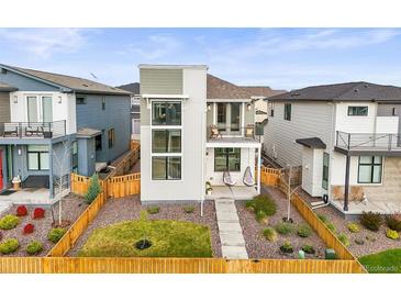 Modern two-story home features fenced yard, balcony, and stylish architectural details at 21440 E 61St Dr, Aurora, CO 80019