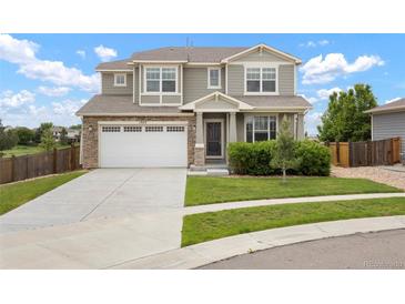 Inviting two-story home featuring a well-maintained lawn, stone accents, and a spacious two-car garage at 1523 Honeysuckle Ct, Brighton, CO 80601